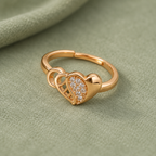 Dilruba Interlocking Heart Rose Gold-Tone Ring on a sage suede backdrop