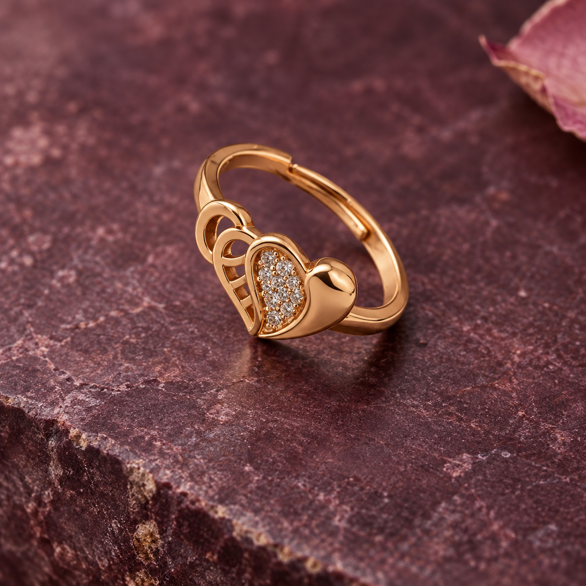 Dilruba Interlocking Heart Rose Gold-Tone Ring on a plum stone backdrop