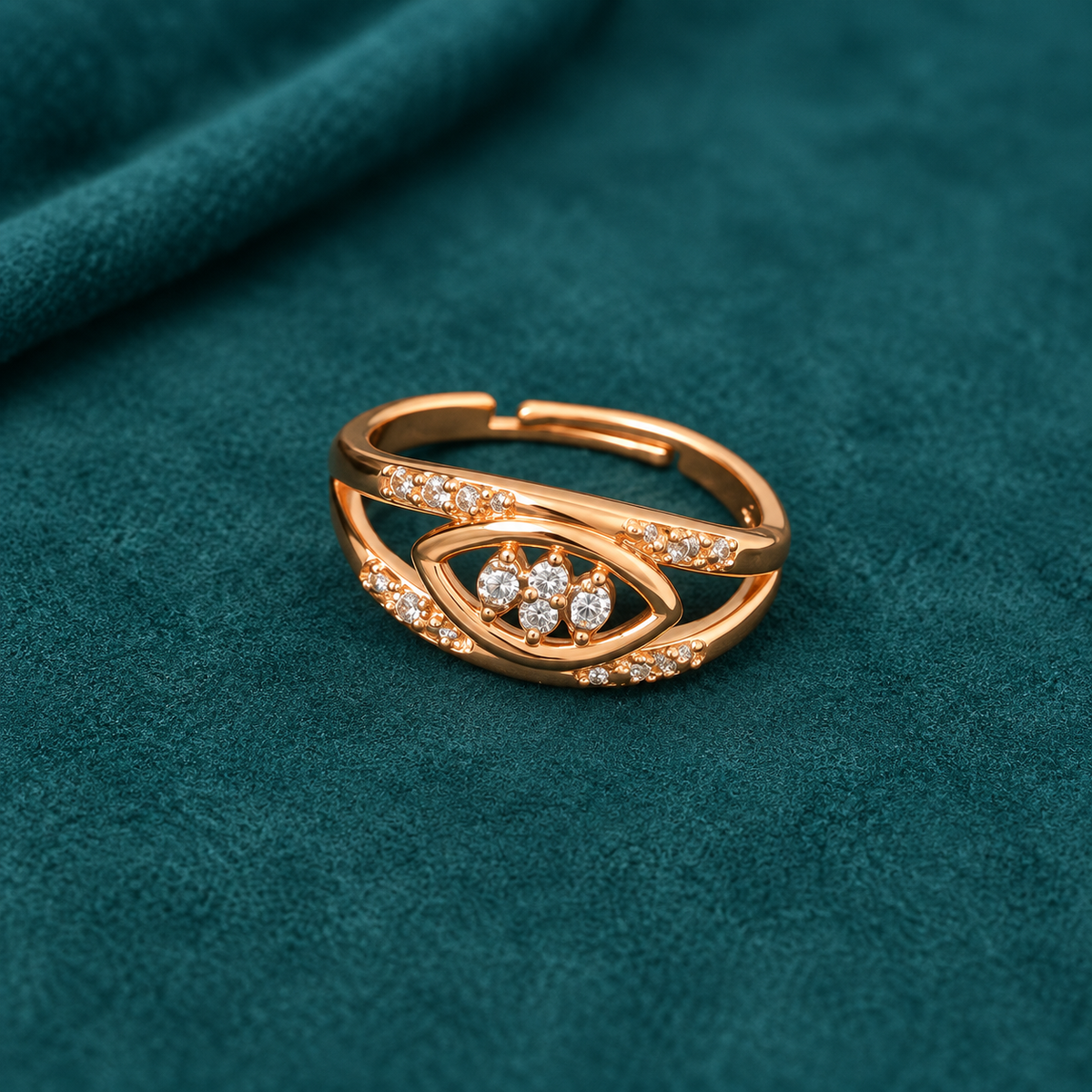 Naina Sparkle Rose Gold-Tone Crossover Ring on a teal suede backdrop